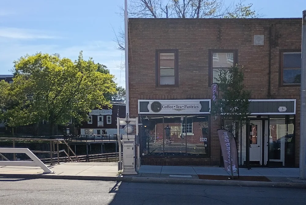 A brick storefront on North Main Street with a Coffee, Tea, Pastries sign, beside the canal
