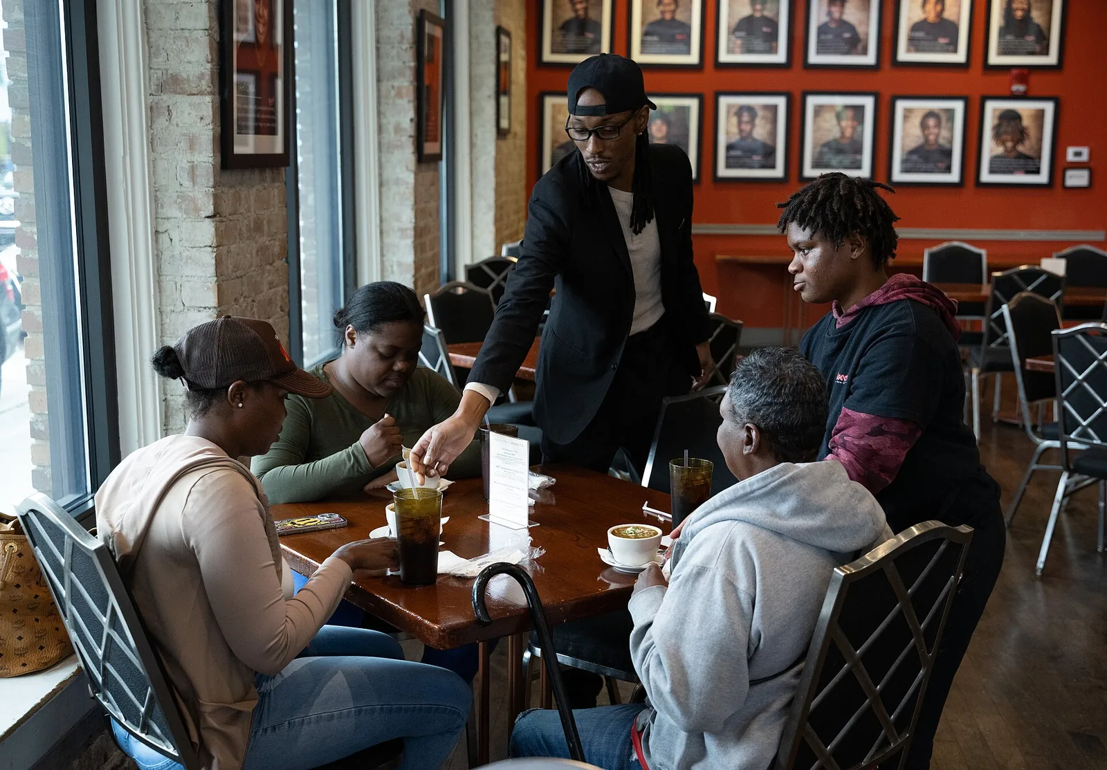 A server bringing drinks to four people at a table by a window